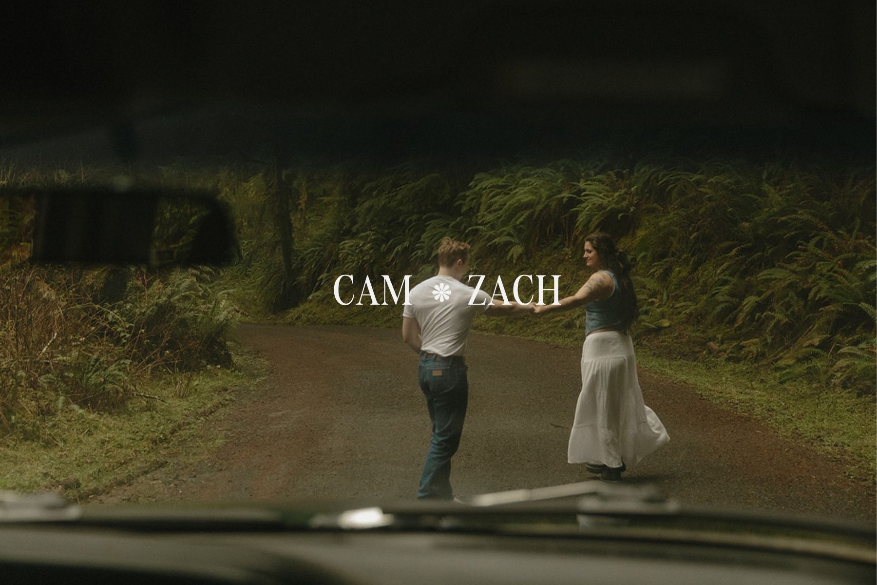 Couple walking hand in hand on a moody forest road during an Oregon Coast engagement session near Seaside, Oregon