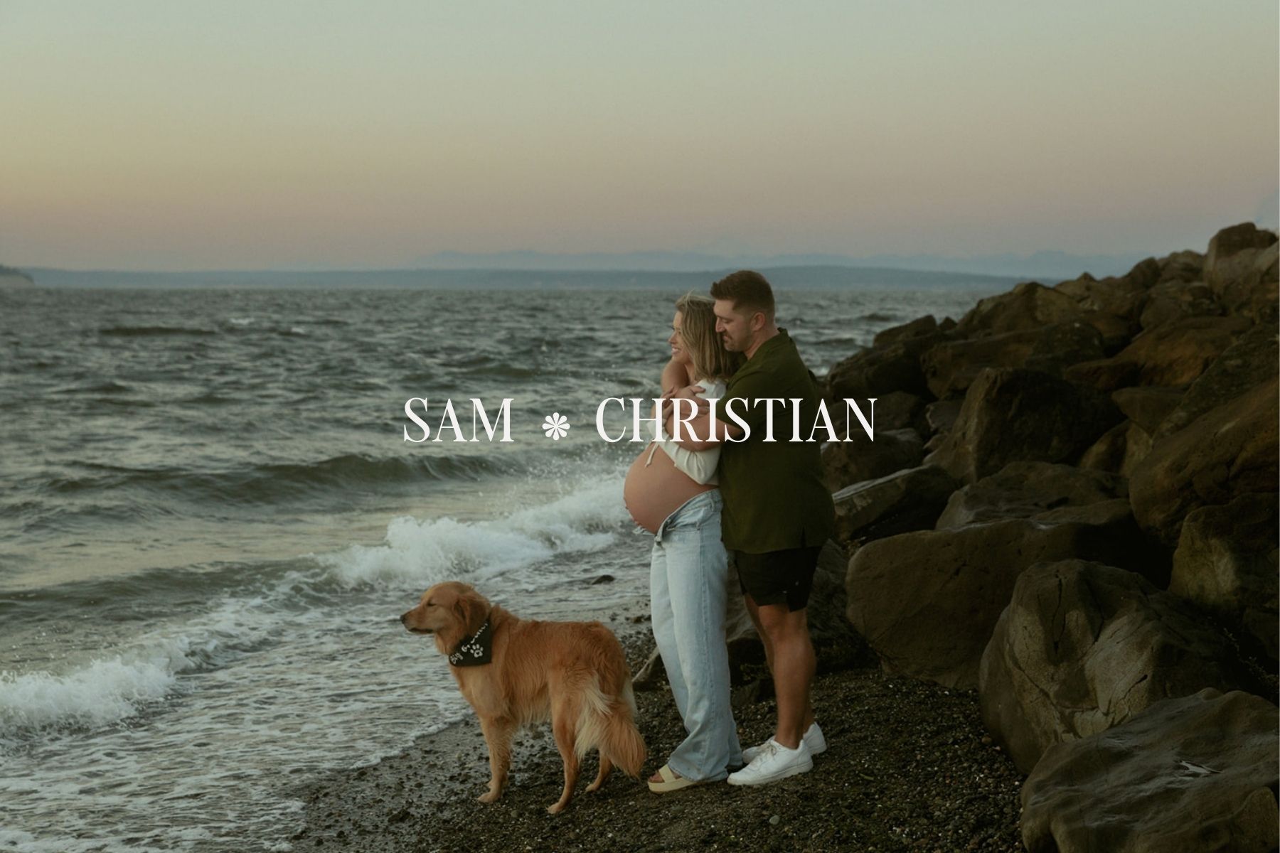 Pregnant couple with their dog standing along the water at sunset during a maternity session at Mukilteo Lighthouse Park in Washington.
